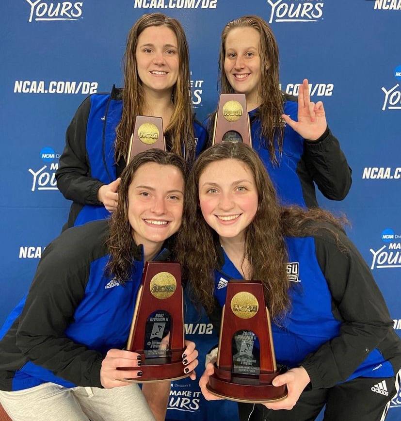 Four female identifying student-athlete swimmers posing with their NCAA trophies